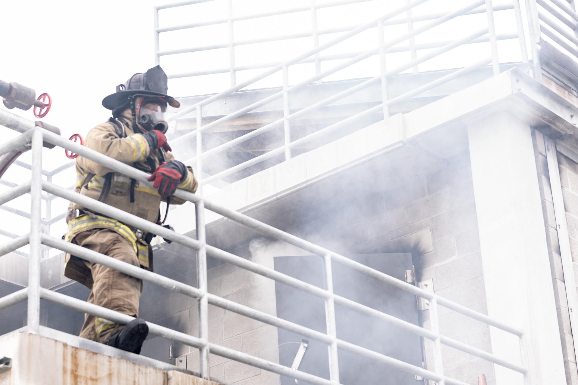 Firefighter on balcony, looking out, surrounded by smoke